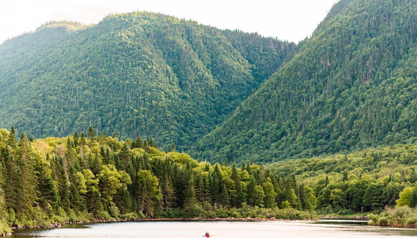 Paysage de la vallée de la Jacques-Cartier avec un canot lointain dans la rivière, au Parc national de la Jacques-Cartier.