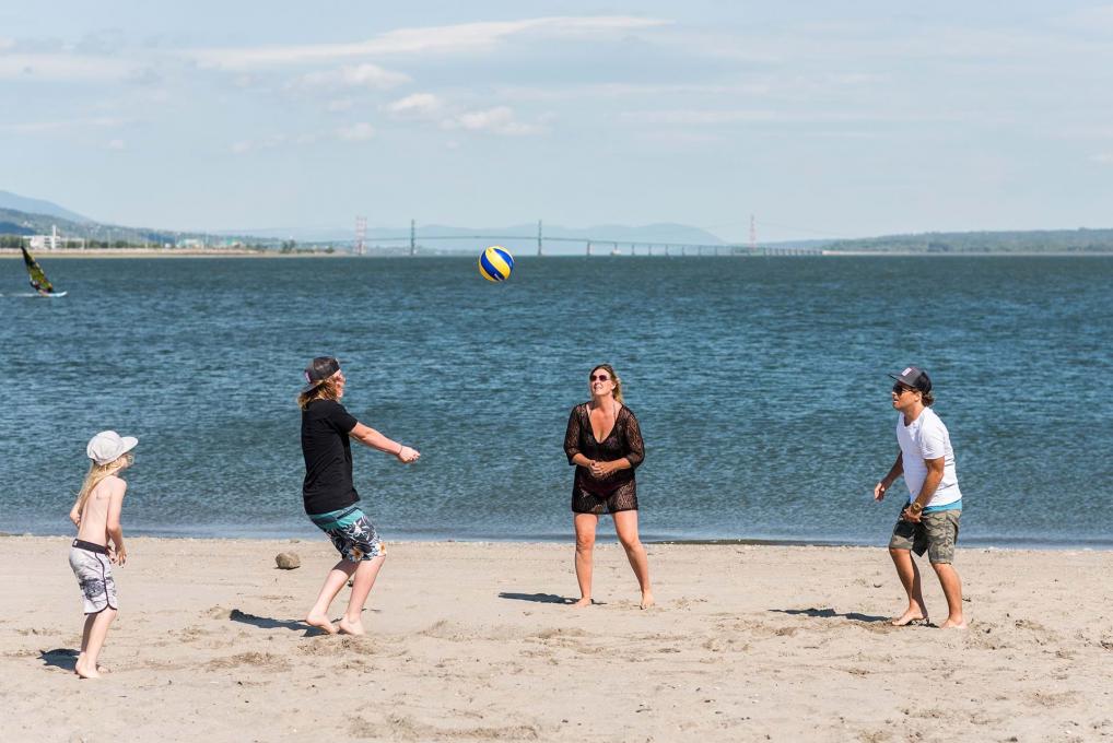 Une famille joue au volleyball sur le bord du fleuve, à la plage de la Baie de Beauport.
